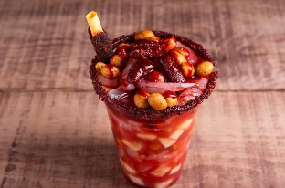 Chamoy sauce served over a Mexican snack with chili powder, peanuts, and fruit, showcasing sweet, spicy, and tangy sauce.