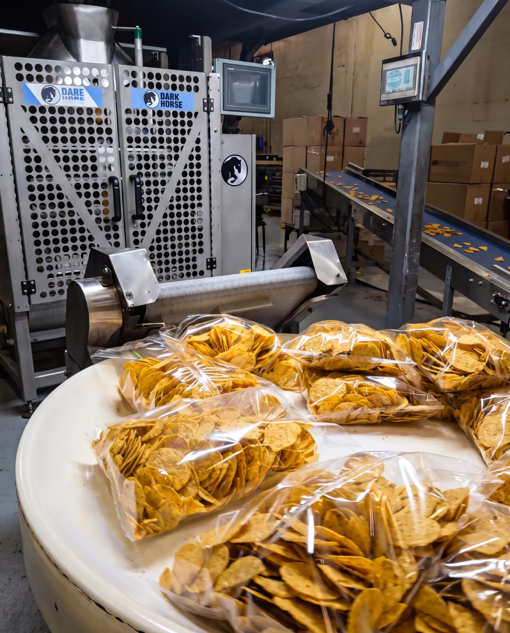 Packaged tortilla products moving along stainless steel conveyor line at Orendain Brands facility, representing private label manufacturing capacity